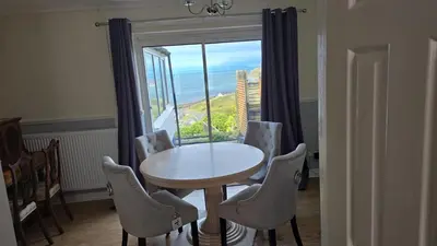 a table and chairs in a room with a large window at Beach villa in Parton