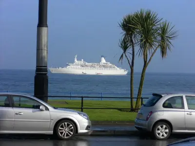 two cars parked in front of a cruise ship in the ocean at isleofmanholidayapartment in Douglas