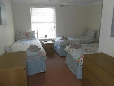 a room with three beds and a window at isleofmanholidayapartment in Douglas