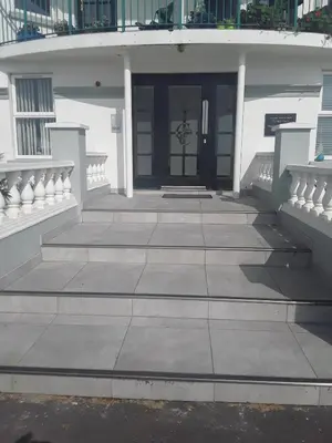 a white building with a black door and stairs at isleofmanholidayapartment in Douglas