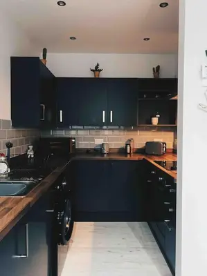 a kitchen with black cabinets and a sink at Lakes Loft in Cockermouth