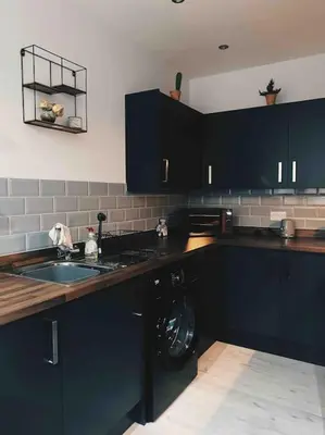 a kitchen with black cabinets and a washing machine at Lakes Loft in Cockermouth