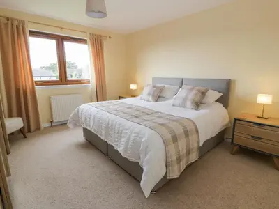 a bedroom with a large bed and a window at Seascape in Dalbeattie