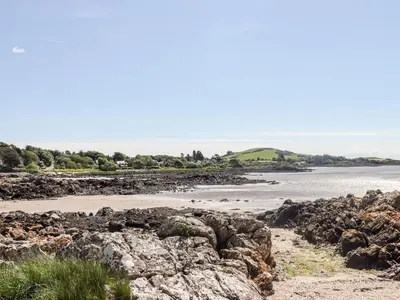 a beach with rocks and the ocean in the background at Seascape in Dalbeattie