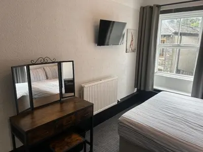 a bedroom with a bed and a dresser with a mirror at The White Lion Inn in Penrith