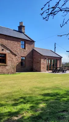 a brick building with a picnic table in front of it at Family friendly farmhouse with games and cinema room in Glencaple