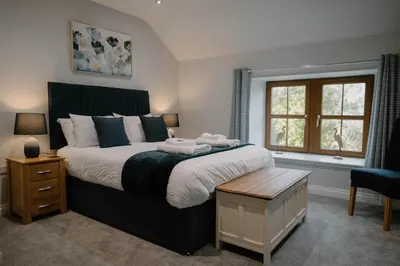 a bedroom with a large bed and a window at Family friendly farmhouse with games and cinema room in Glencaple