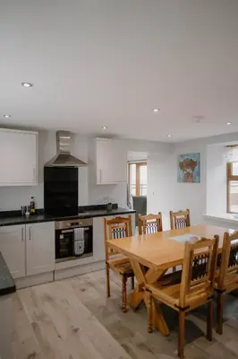 a kitchen with a wooden table and wooden chairs at Family friendly farmhouse with games and cinema room in Glencaple