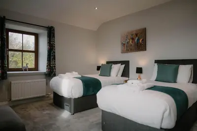 a bedroom with two beds and a window at Family friendly farmhouse with games and cinema room in Glencaple