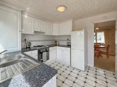 a kitchen with white cabinets and a white refrigerator at Tredegar in Newton Stewart