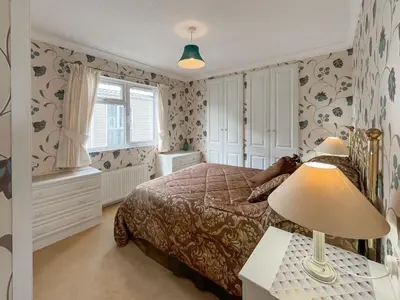 a bedroom with a bed and a lamp on a table at Tredegar in Newton Stewart