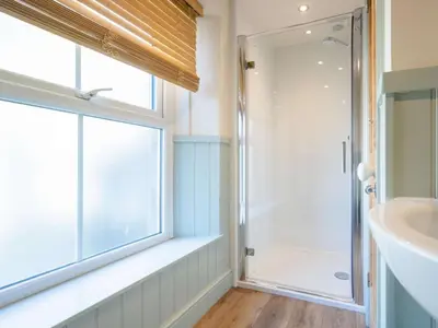 a bathroom with a shower and a sink and a window at The Gables in Keswick