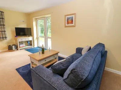 a living room with a blue couch and a tv at The Nest in Carlisle