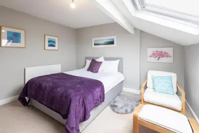 a bedroom with a purple bed and a white chair at Hampton Manor House - 9 Bedrooms in St Bees