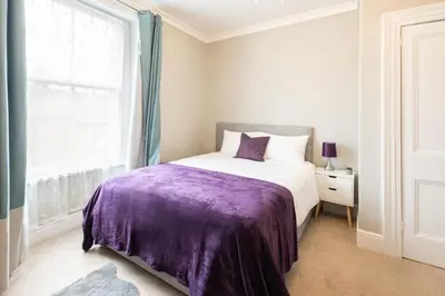 a bedroom with a bed with a purple blanket at Hampton Manor House - 9 Bedrooms in St Bees