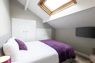 a bedroom with a white bed and a flat screen tv at Hampton Manor House - 9 Bedrooms in St Bees