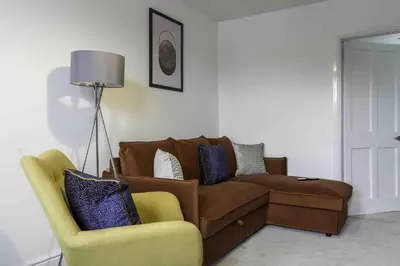 a living room with a brown couch and a chair at Strath Apartment in Strathaven