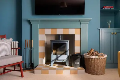 a living room with a fireplace with a tv above it at Queensberry Cottage in Thornhill