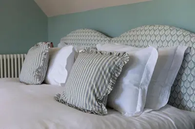 a bed with four pillows on top of it at Queensberry Cottage in Thornhill
