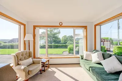 a living room with a green couch and a window at Anthony House in Kippford