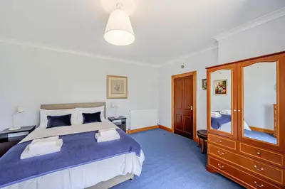 a bedroom with a large bed and a mirror at Anthony House in Kippford