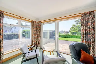 a living room with a large window and chairs at Anthony House in Kippford