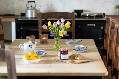 a table with a vase of flowers and a vase of fruit at Bank Barn, Wreay in Penrith