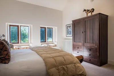 a bedroom with a large bed and a wooden cabinet at Bank Barn, Wreay in Penrith