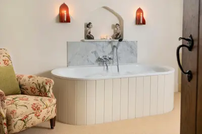 a bathroom with a tub with a sink and a chair at Bank Barn, Wreay in Penrith