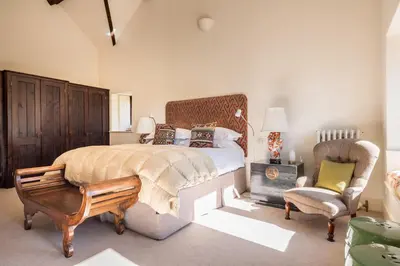 a bedroom with a king sized bed and a chair at Bank Barn, Wreay in Penrith