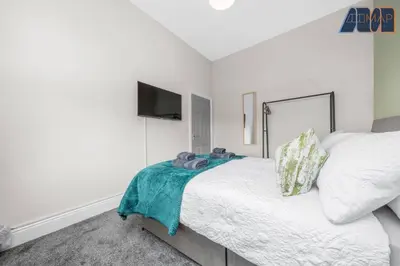 a white bedroom with a bed and a flat screen tv at Carlisle 3Bed Sleeps 6 in Carlisle