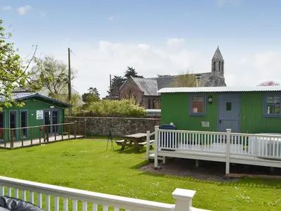 a green house with a bench in a yard at Sian's Shepherds Hut - Uk43561 in Bowness-on-Solway