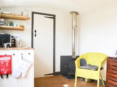 a kitchen with a yellow chair and a stove at Hannah's Shepherds Hut - Uk43564 in Bowness-on-Solway
