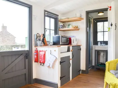 a kitchen with white cabinets and a gray door at Jamie's Shepherds Hut - Uk43566 in Bowness-on-Solway