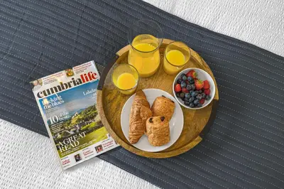 a table with a plate of breakfast food and a box of orange juice at Brundholme House in Keswick