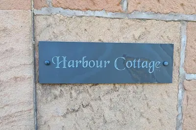 a sign on the side of a brick wall at Harbour cottage Annan in Annan