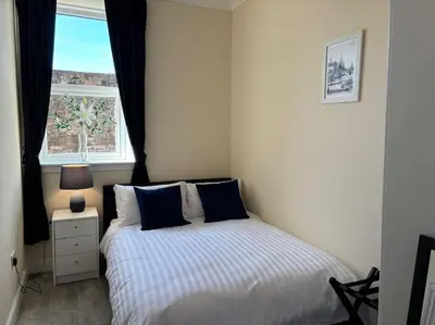 a bedroom with a bed with blue pillows and a window at Harbour cottage Annan in Annan