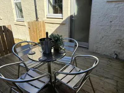 a patio table with two chairs and a bottle of wine at Harbour cottage Annan in Annan