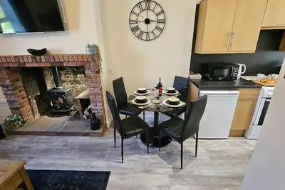 a kitchen with a table with chairs and a fireplace at Harbour cottage Annan in Annan