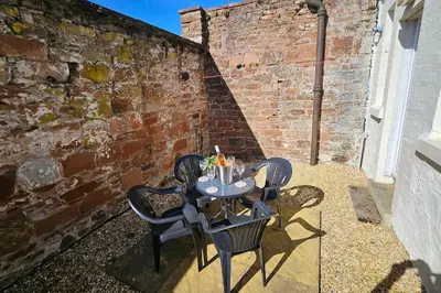 a table and chairs on a patio next to a brick wall at Quay cottage Annan in Annan