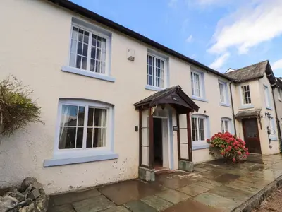 a white house with a door and flowers in front at Holborn Cottage, Blencathra Street in Keswick