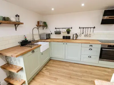 a kitchen with white cabinets and wooden counter tops at Holborn Cottage, Blencathra Street in Keswick