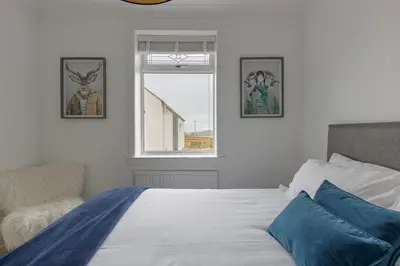 a bedroom with a bed with blue pillows and a window at The Paddock at Brickrow Farm in Ayr