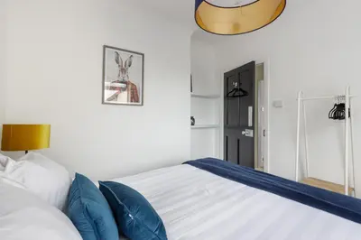 a bedroom with a large bed with blue pillows at The Paddock at Brickrow Farm in Ayr