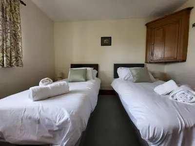 two beds in a room with white sheets and towels at Wheelwrights House in Ambleside