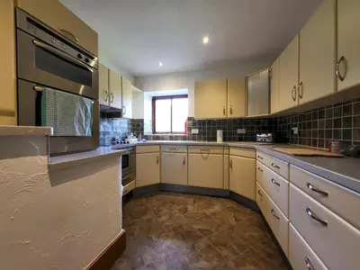 a large kitchen with white cabinets and a window at Wheelwrights House in Ambleside