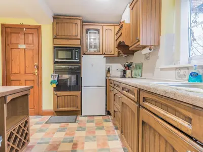 a kitchen with wooden cabinets and a white refrigerator at Stanwix Cottage in Carlisle