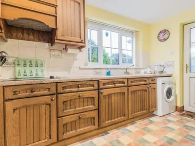a kitchen with wooden cabinets and a washer and dryer at Stanwix Cottage in Carlisle