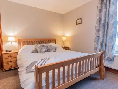a bedroom with a wooden bed and a window at Stanwix Cottage in Carlisle