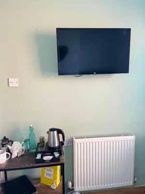 a flat screen tv hanging on a wall above a radiator at Cartref Guest House in Carlisle